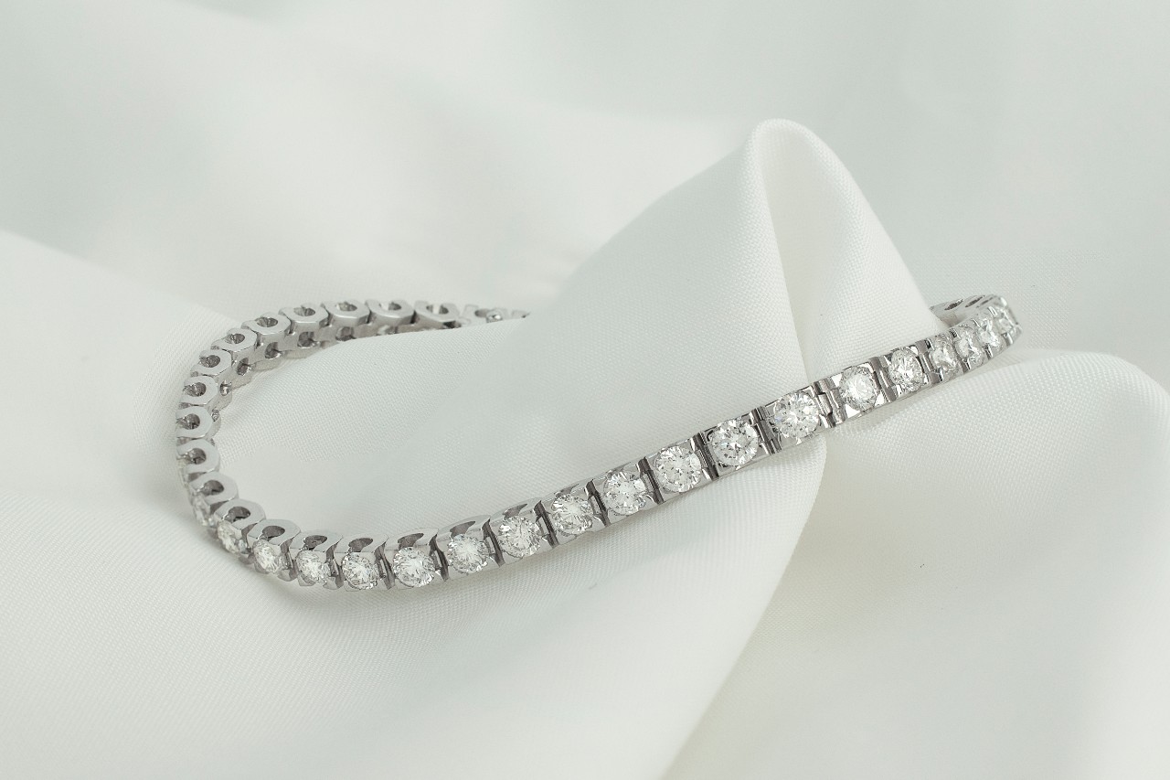 a white gold diamond tennis bracelet sitting on a piece of white fabric
