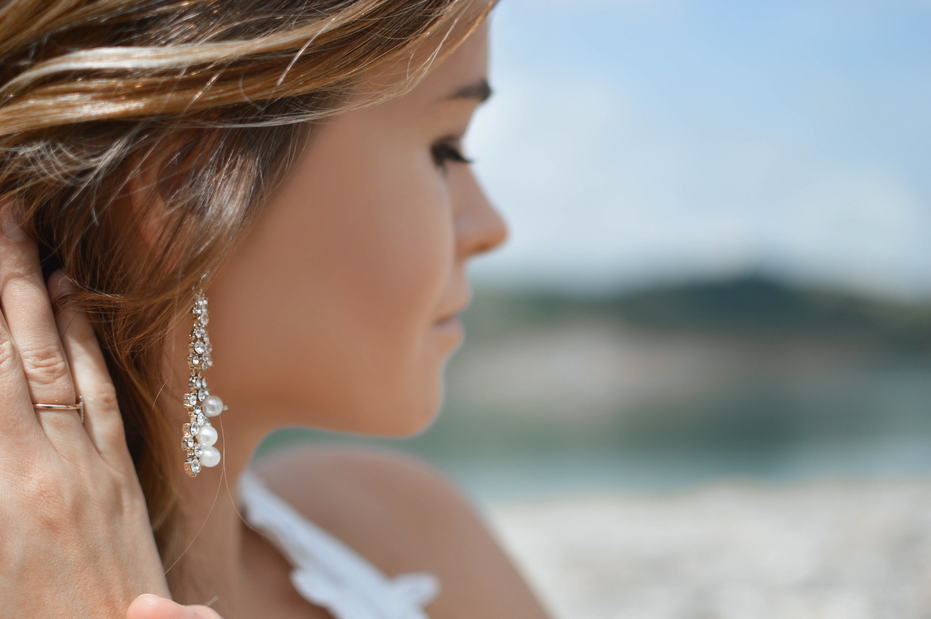 a woman’s profile, highlighting a pair of drop diamond and pearl earrings
