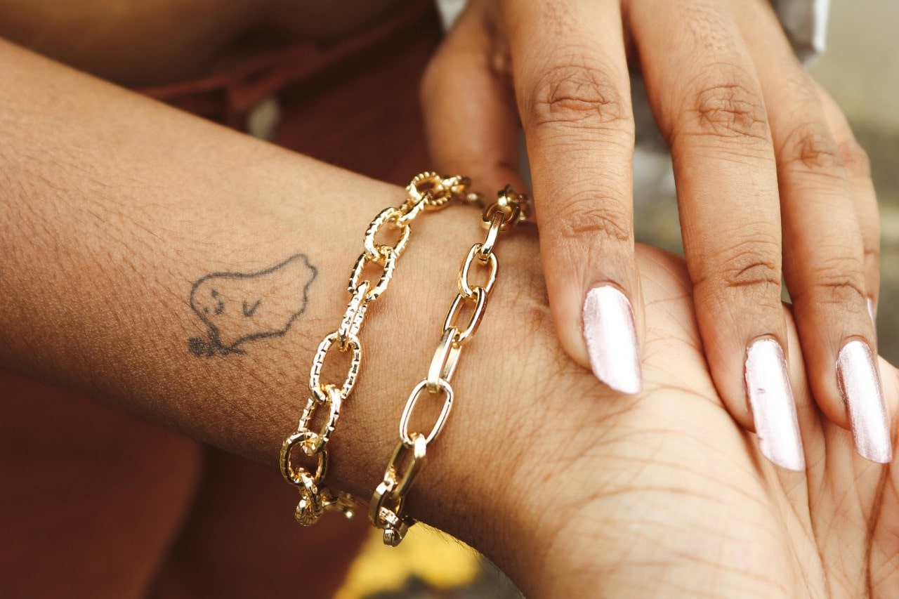 a woman’s wrist adorned with two chunky gold chain bracelets