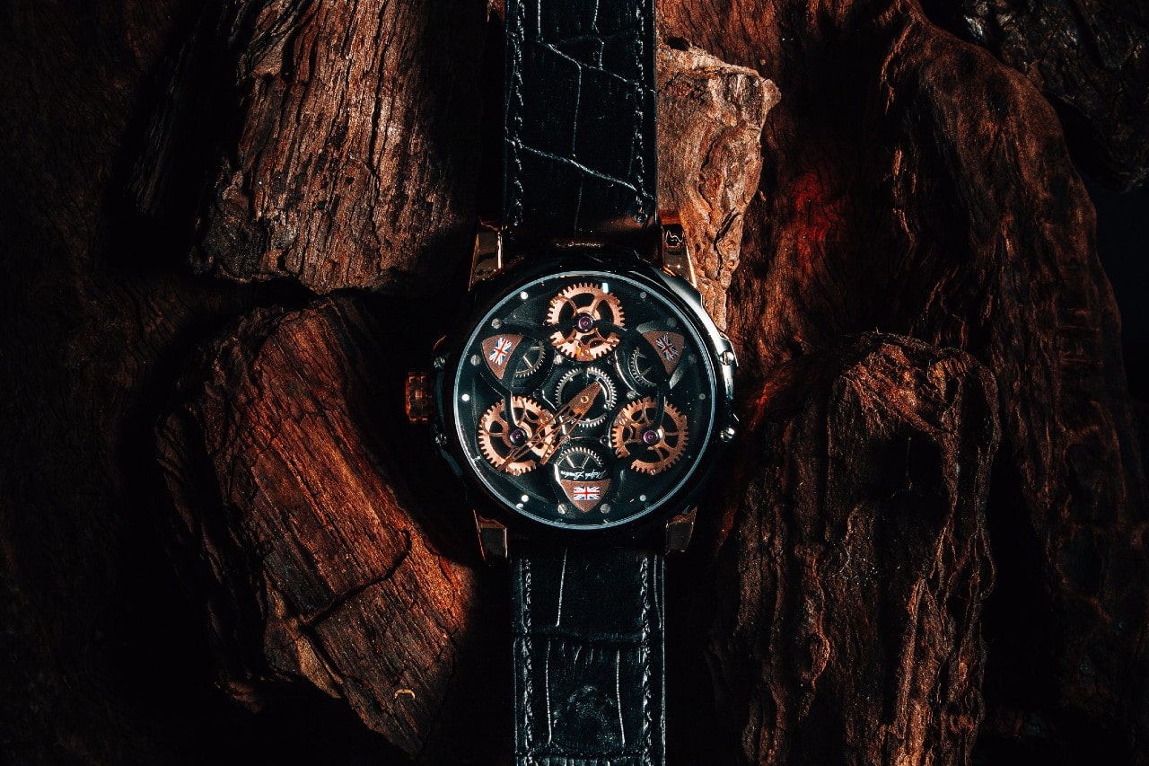 A black, mixed metal skeleton dial watch against a piece of wood
