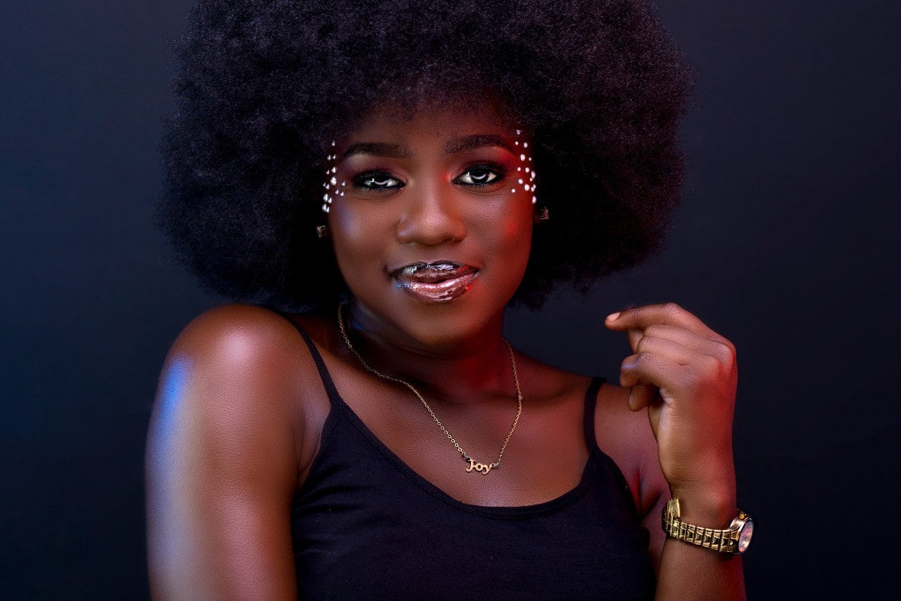 a woman against a dark background wearing glittering makeup and a gold watch