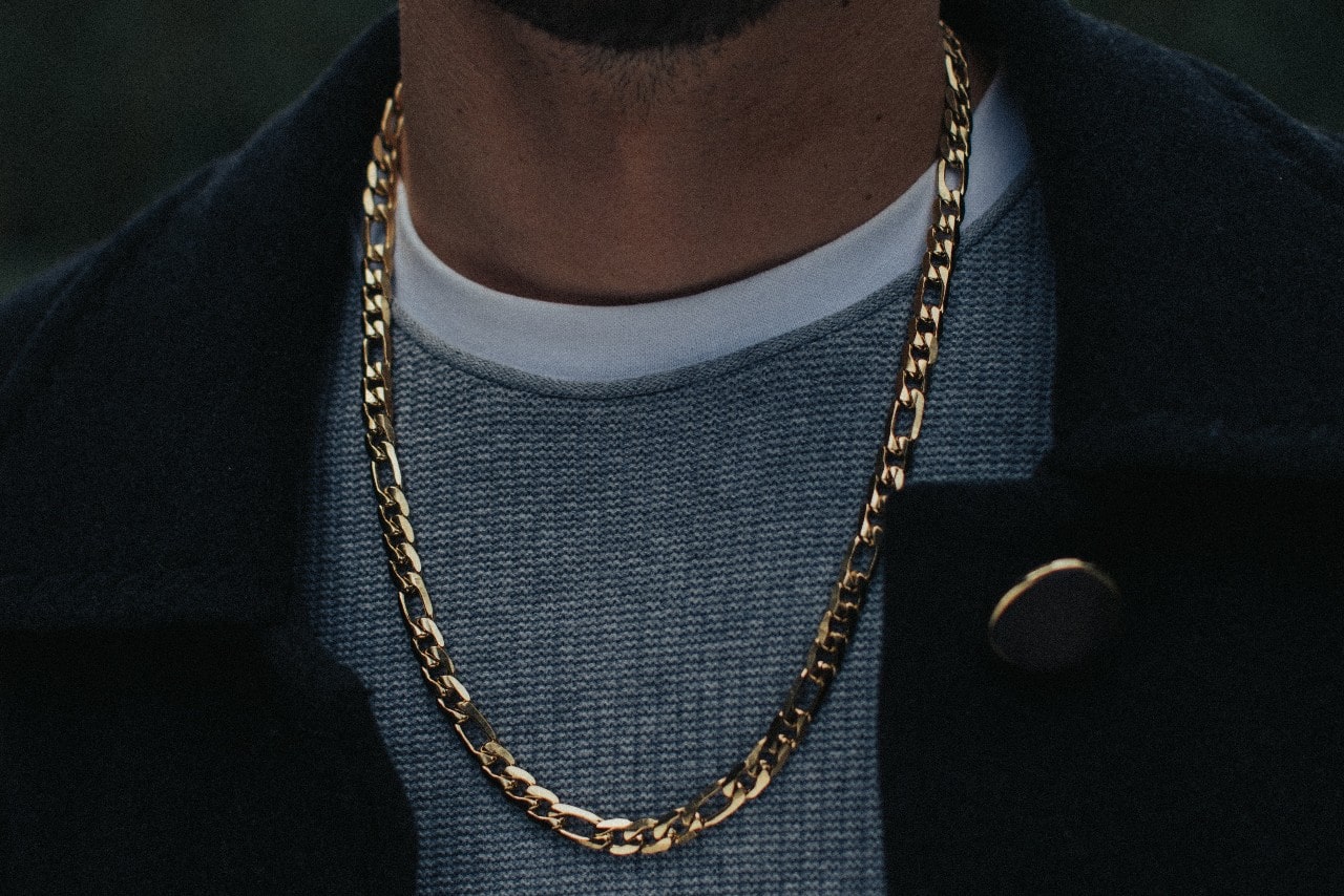 close up image of a man’s neckline wearing a chunky yellow gold chain necklace