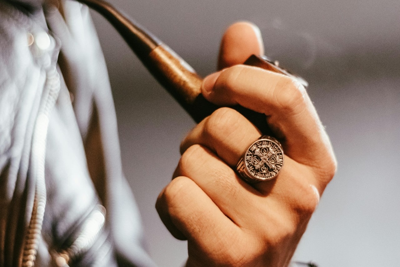 a man smoking a pipe and wearing a bold signet ring