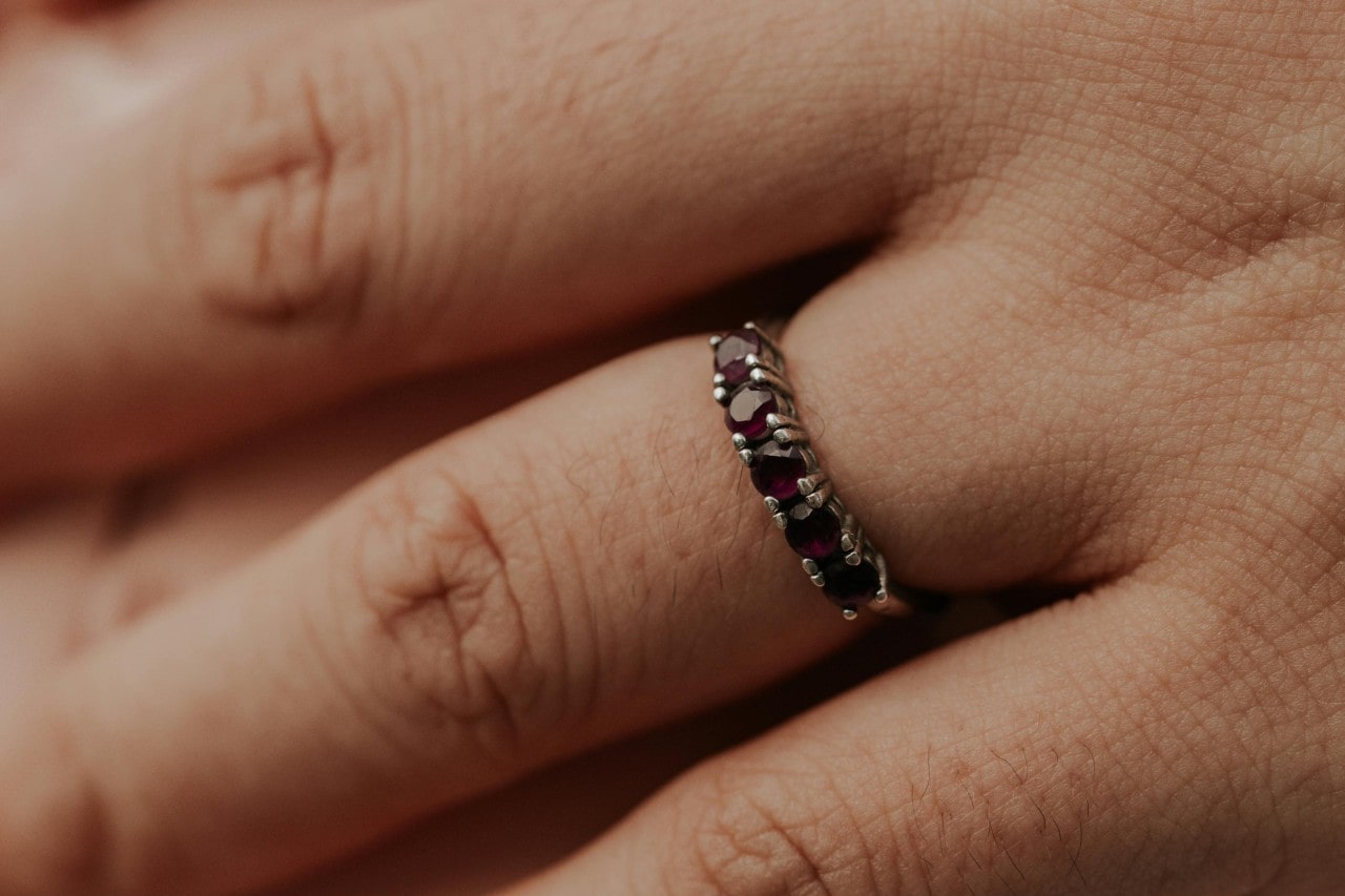 A close-up of a person’s hand adorned with a gemstone wedding band.