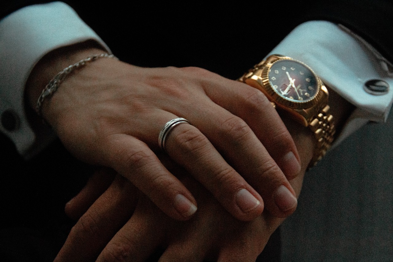 a person wearing a yellow gold watch with their hands stacked one on top of the other