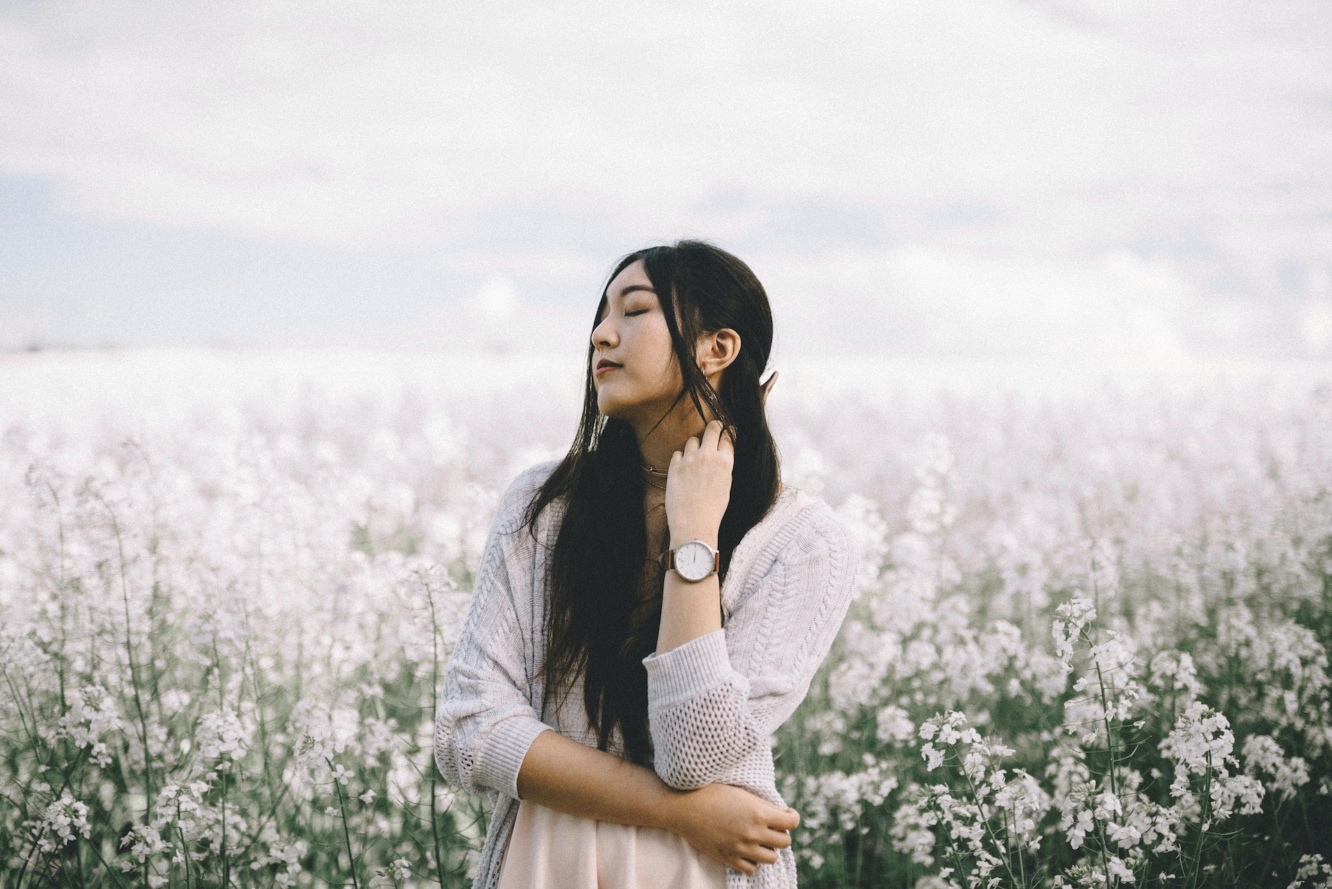 lady standing in a field of flowers wearing a designer watch