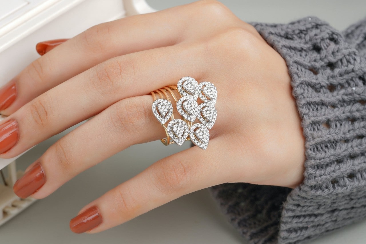 a woman’s hand donning a mixed metal fashion ring with multiple bands and tear shape motifs