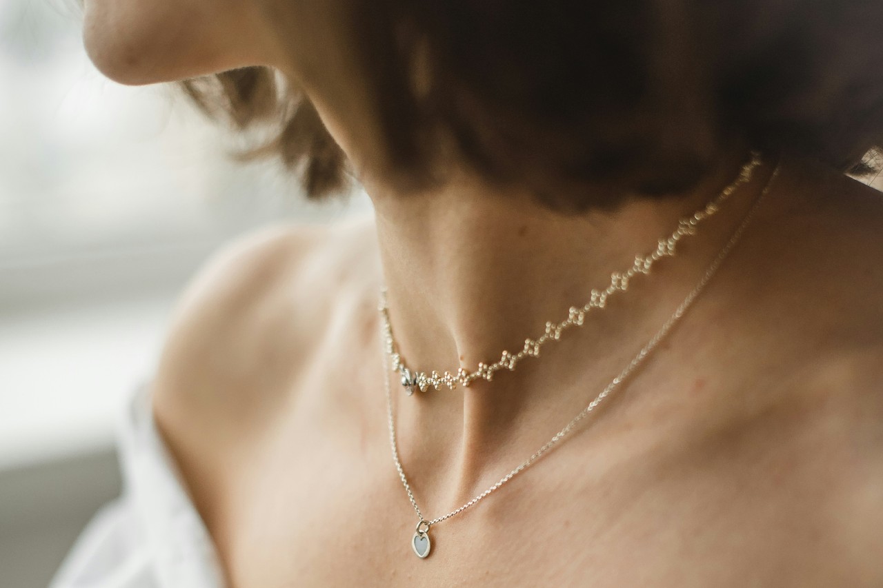 close up image of a woman’s neckline who is wearing two fine gold necklaces