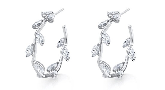 a pair of white gold hoop earrings featuring leaf motifs set with diamonds