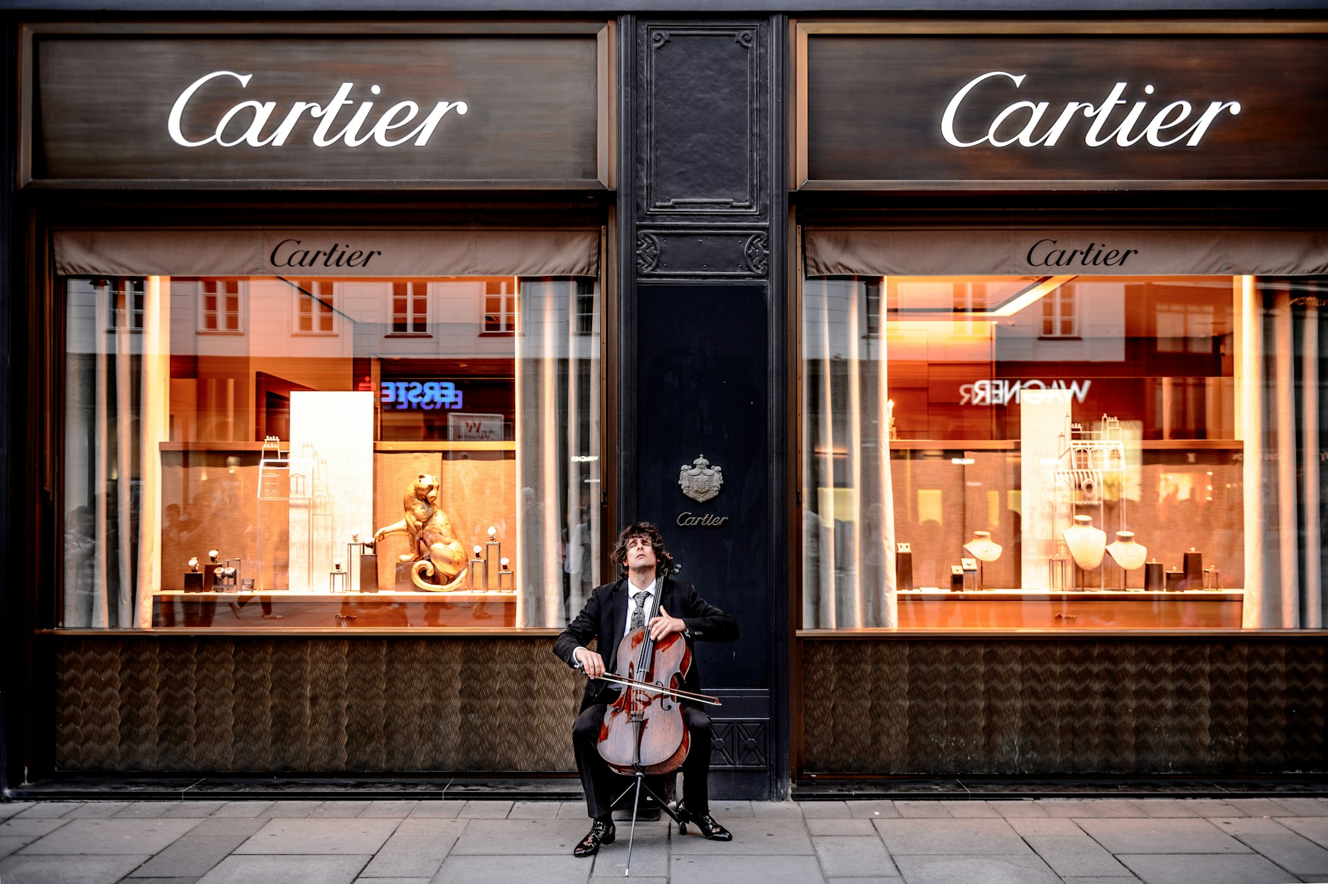 a man playing a cello outside a Cartier jewelry and watch store