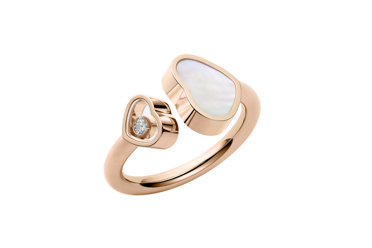 A rose gold ring with two hearts meeting in the middle, one heart containing a diamond and the other with pearl.