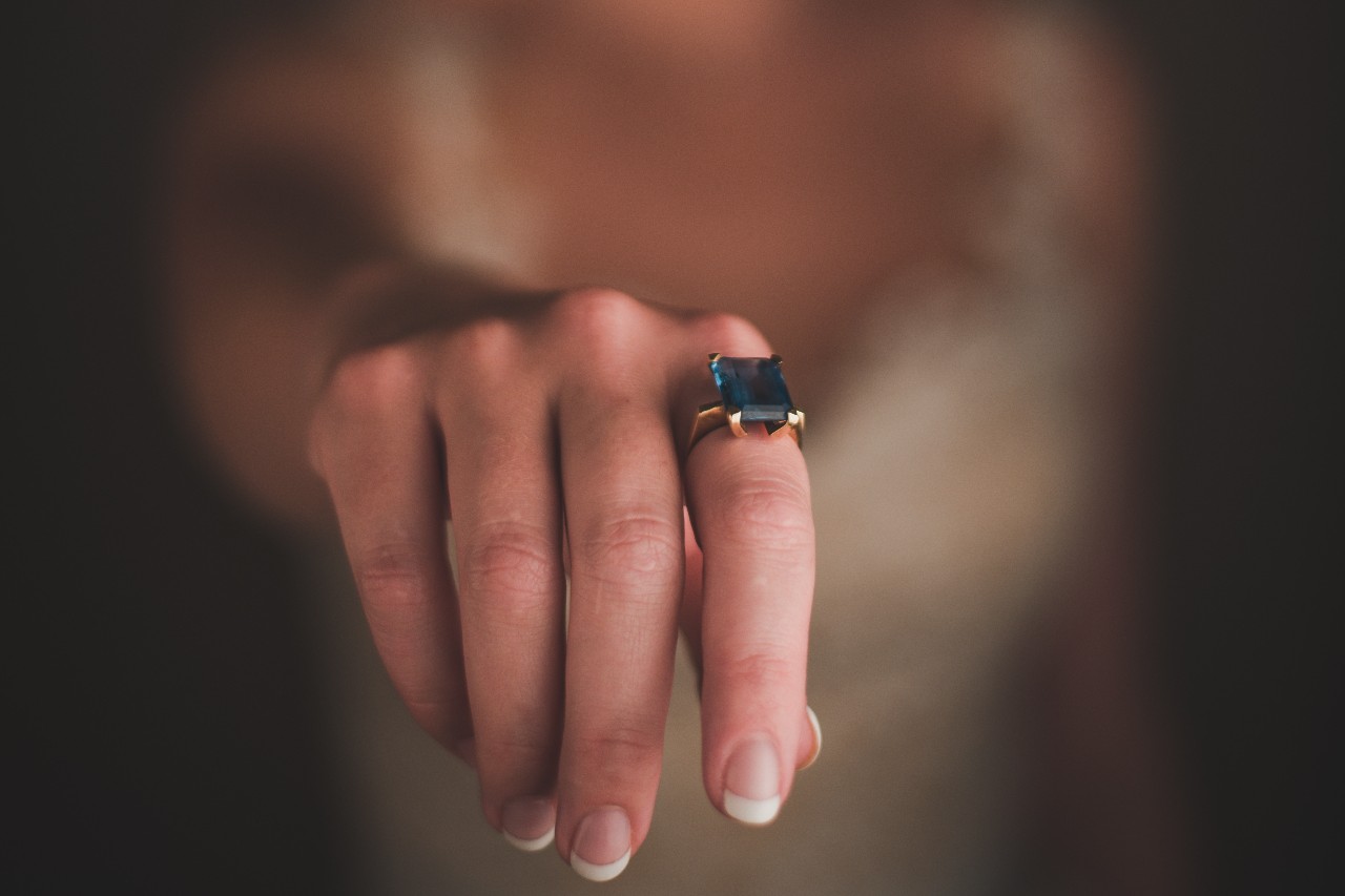 A close up of a person's hand wearing a large alexandrite ring.
