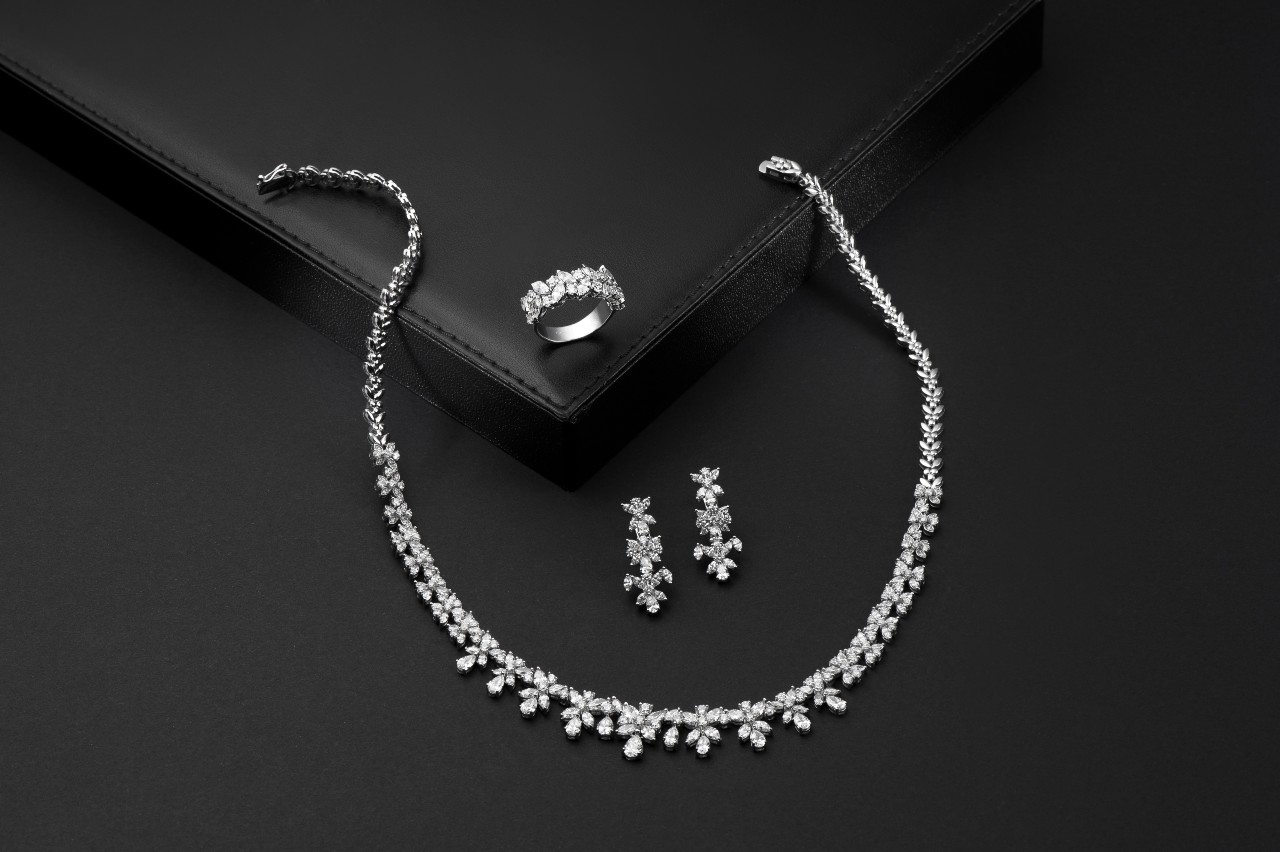 A spectacular set of white gold and diamond jewelry displayed on a black background.