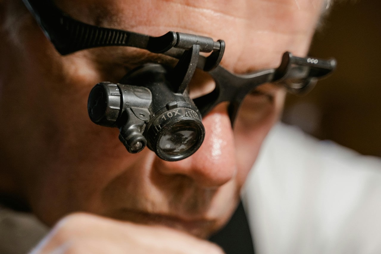 A jeweler inspects something through a magnifying loupe headset, focusing on the details.