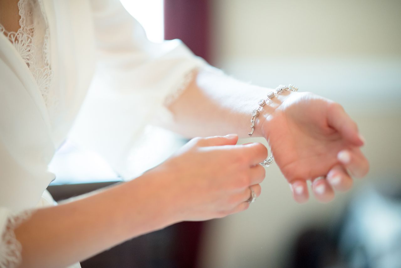 A close-up of a white blouse fixing her white gold diamond bracelet