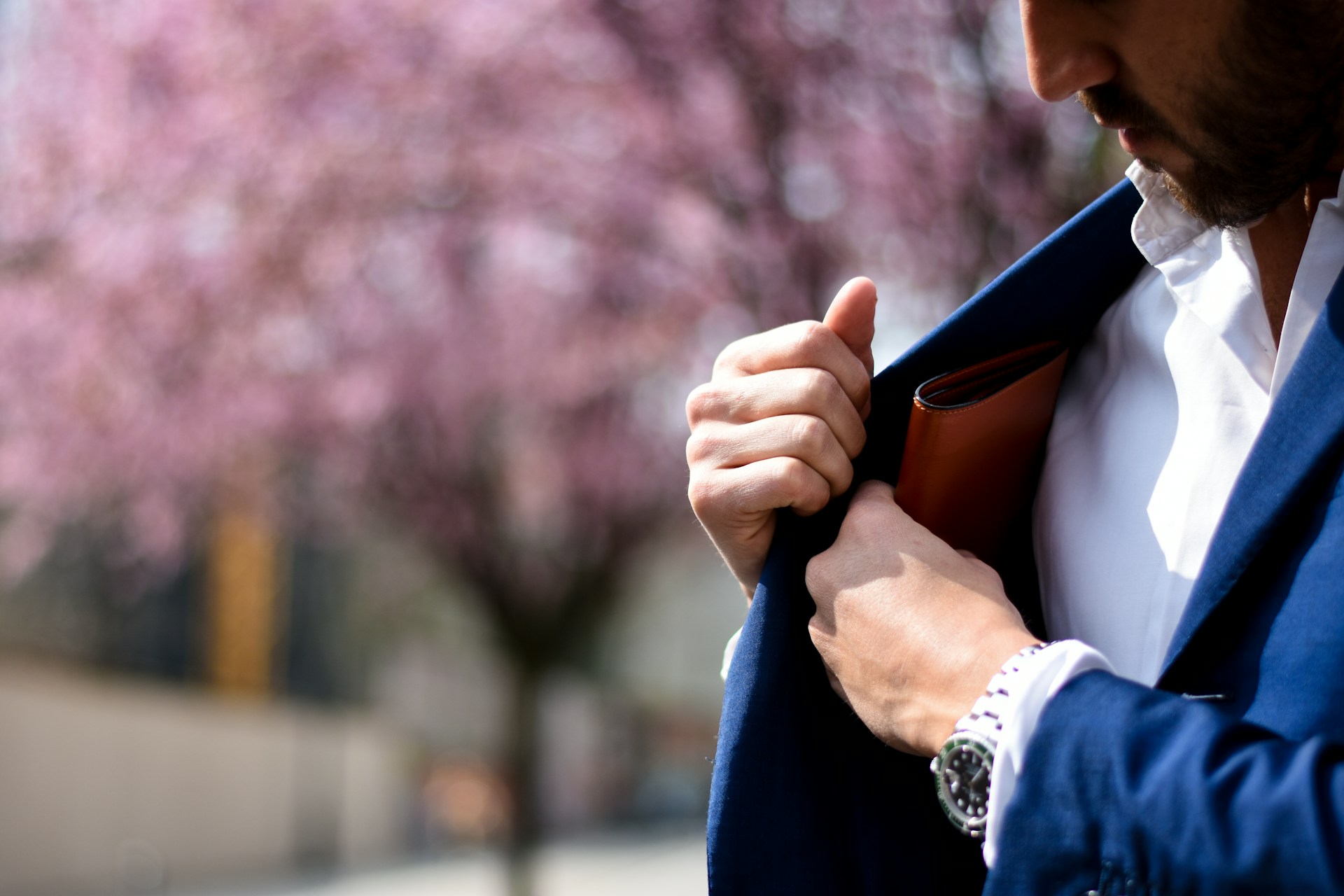 a man wearing a luxury watch taking his wallet out of his jacket