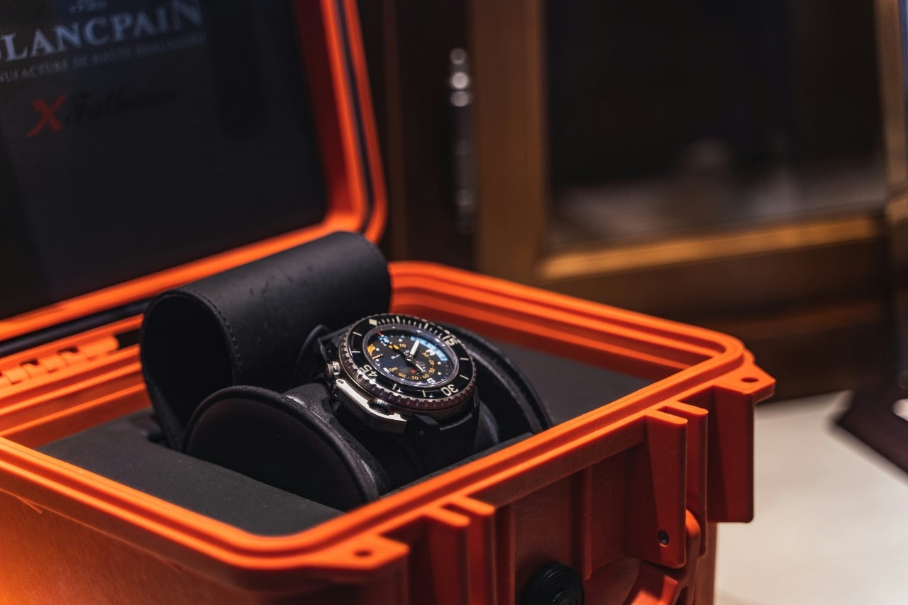 an orange box holding a men’s Blancpain watch with colorful dial details