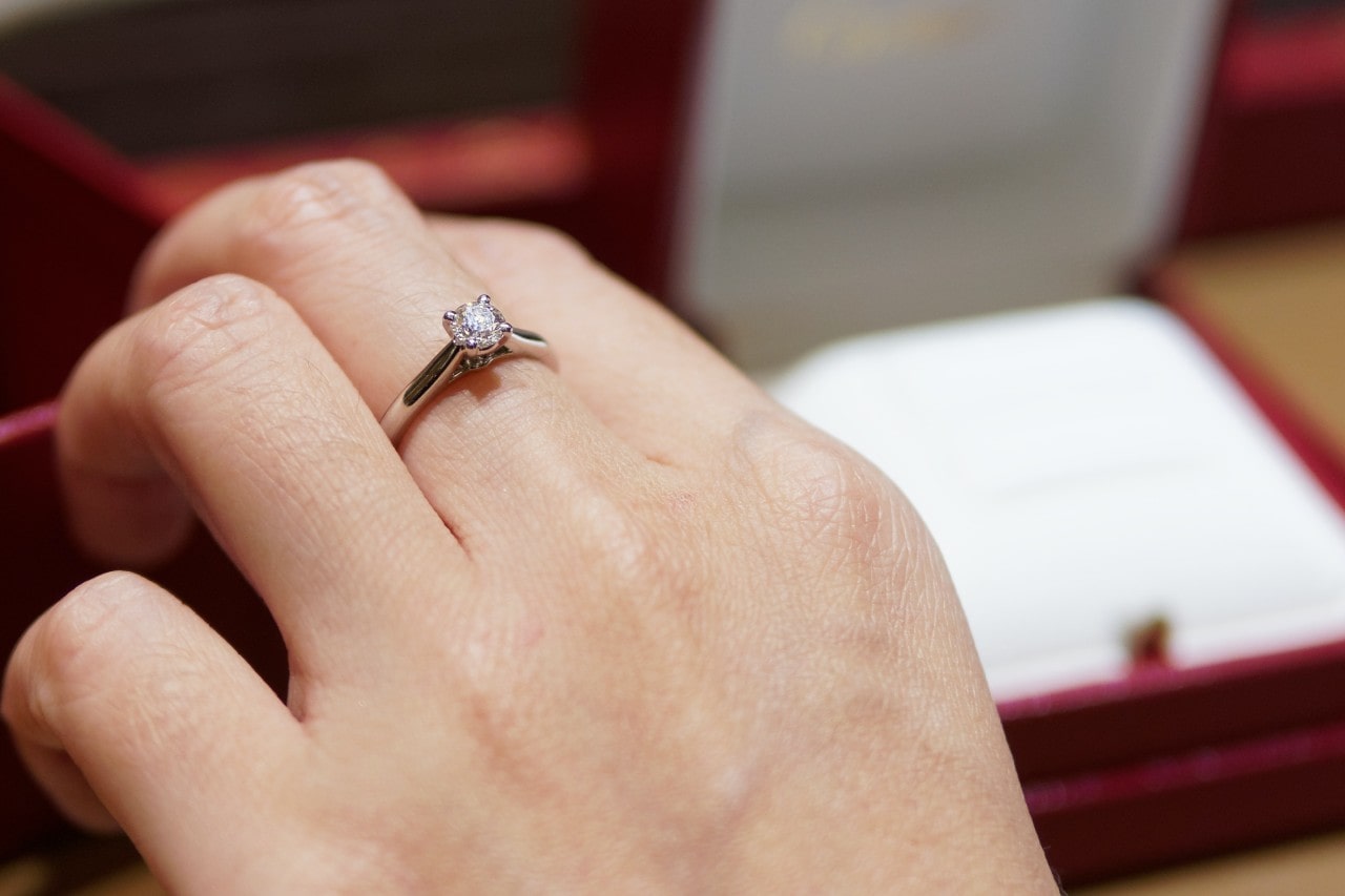 A close-up of a woman’s hand, with an elegant solitaire ring on her middle finger.