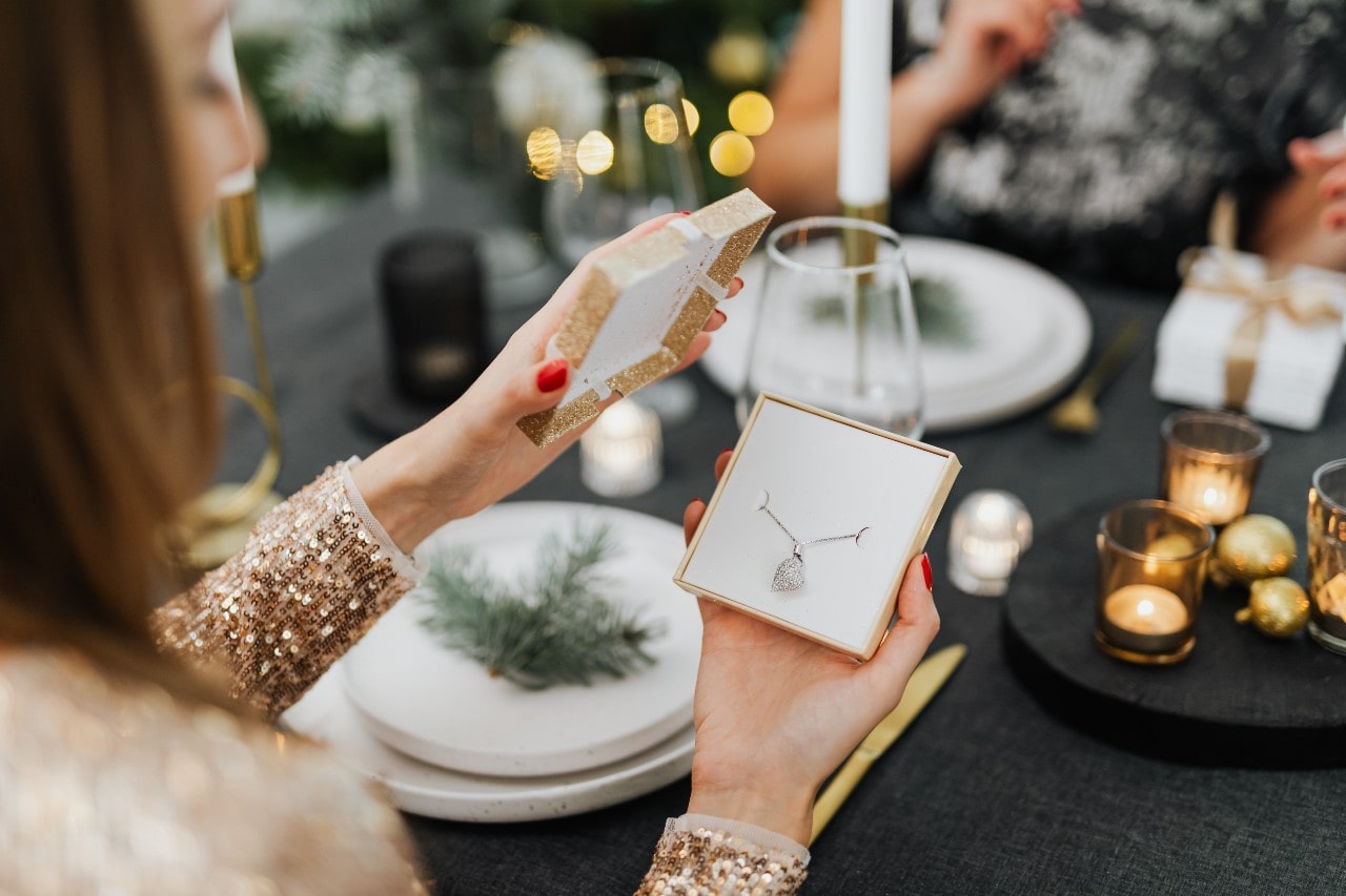 A woman opening a diamond heart necklace over an elegant dinner date for Valentine’s Day