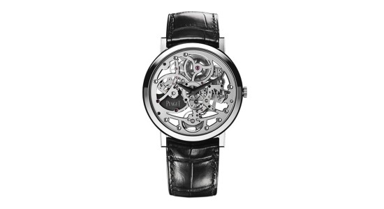 a silver watch with a skeleton dial and a black strap