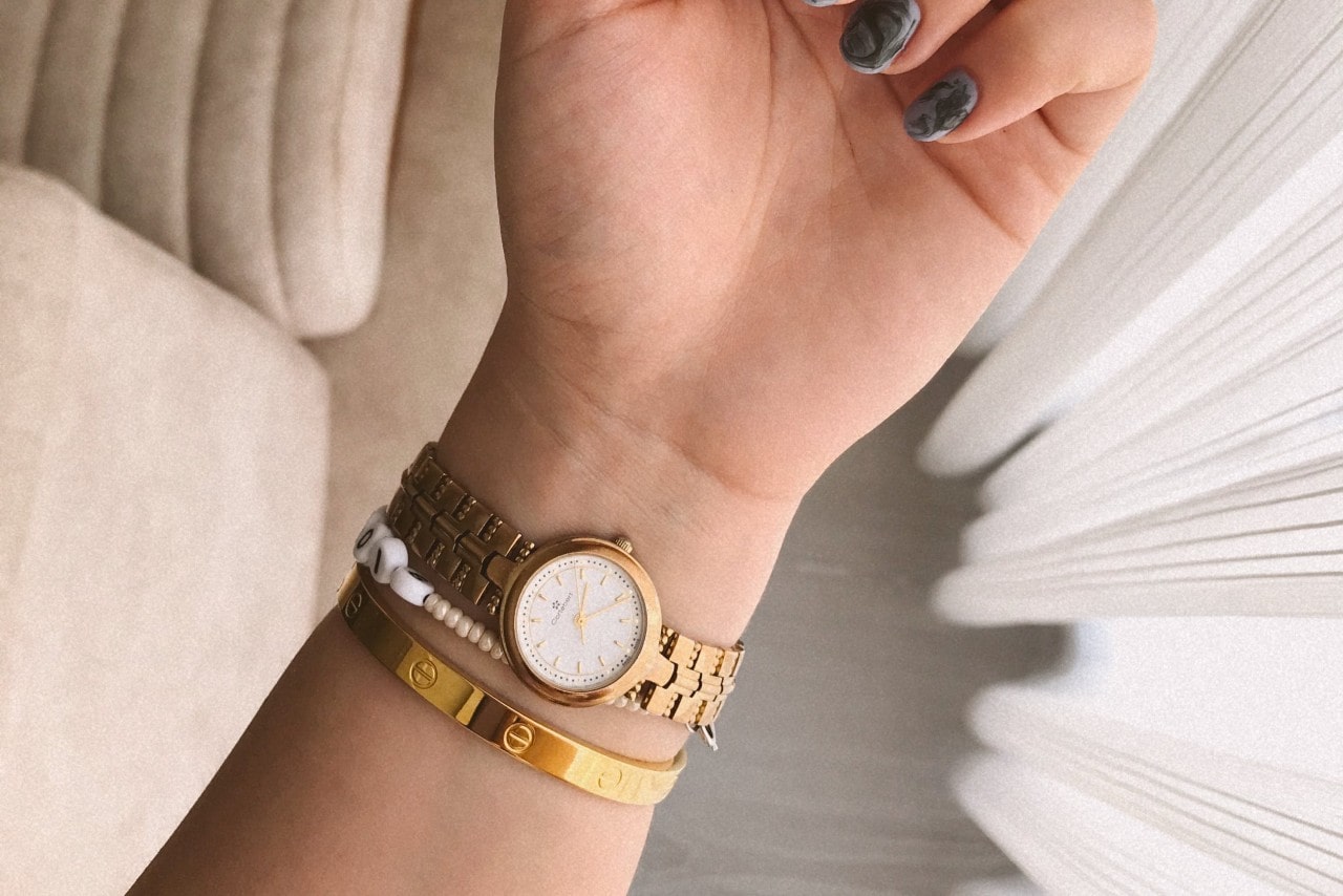 a woman with a gold watch and a couple gold bracelets