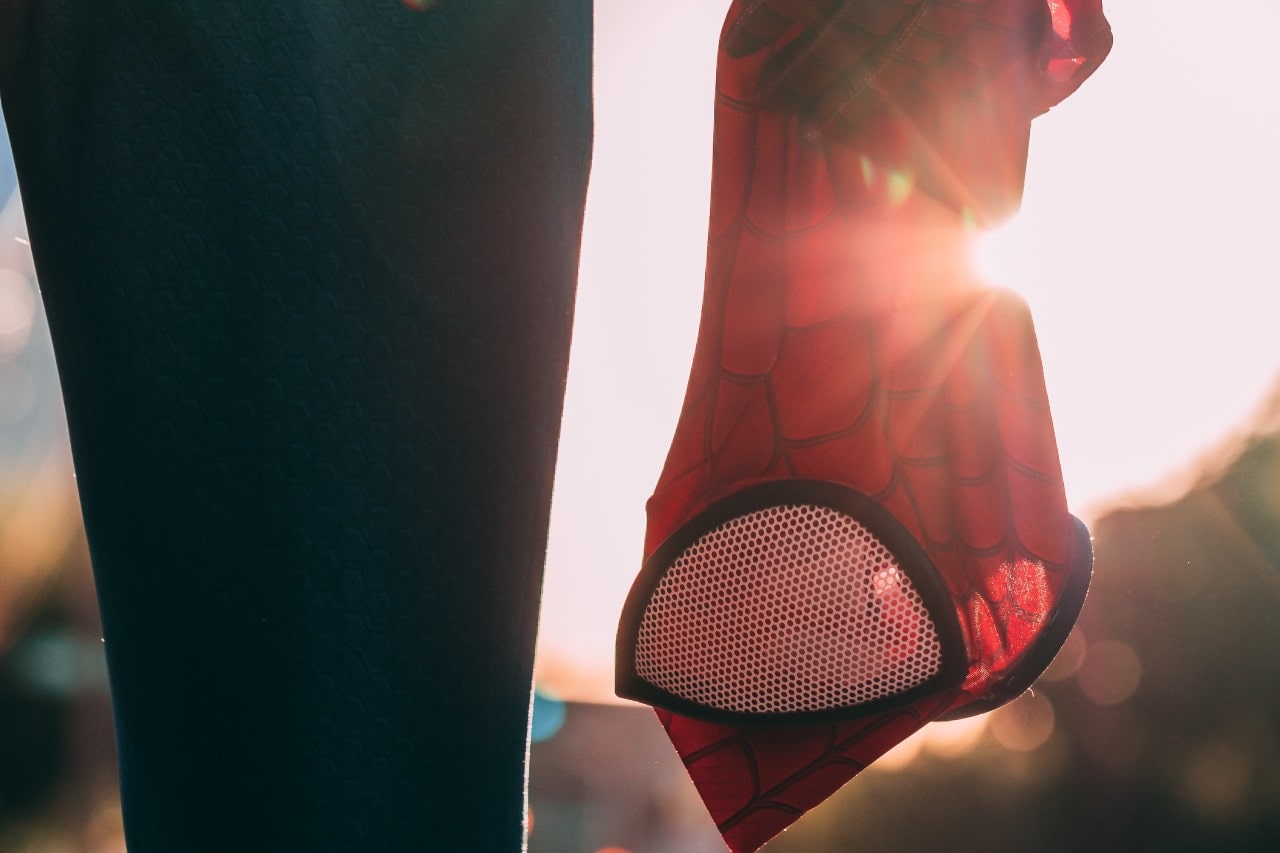 close up image of a person dressed as Spiderman holding their mask at their side