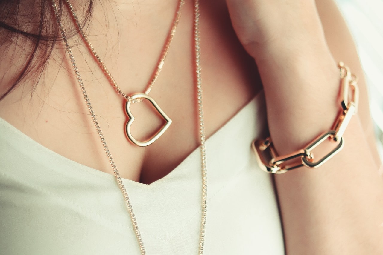 A woman wearing a gold heart necklace and bracelet.
