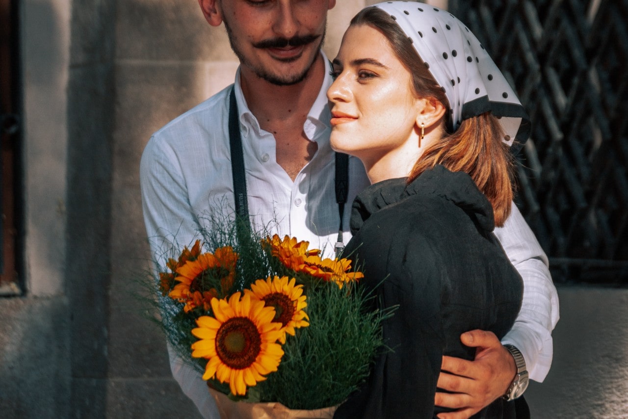 a man and woman embracing, the man wearing a silver watch on his left wrist.