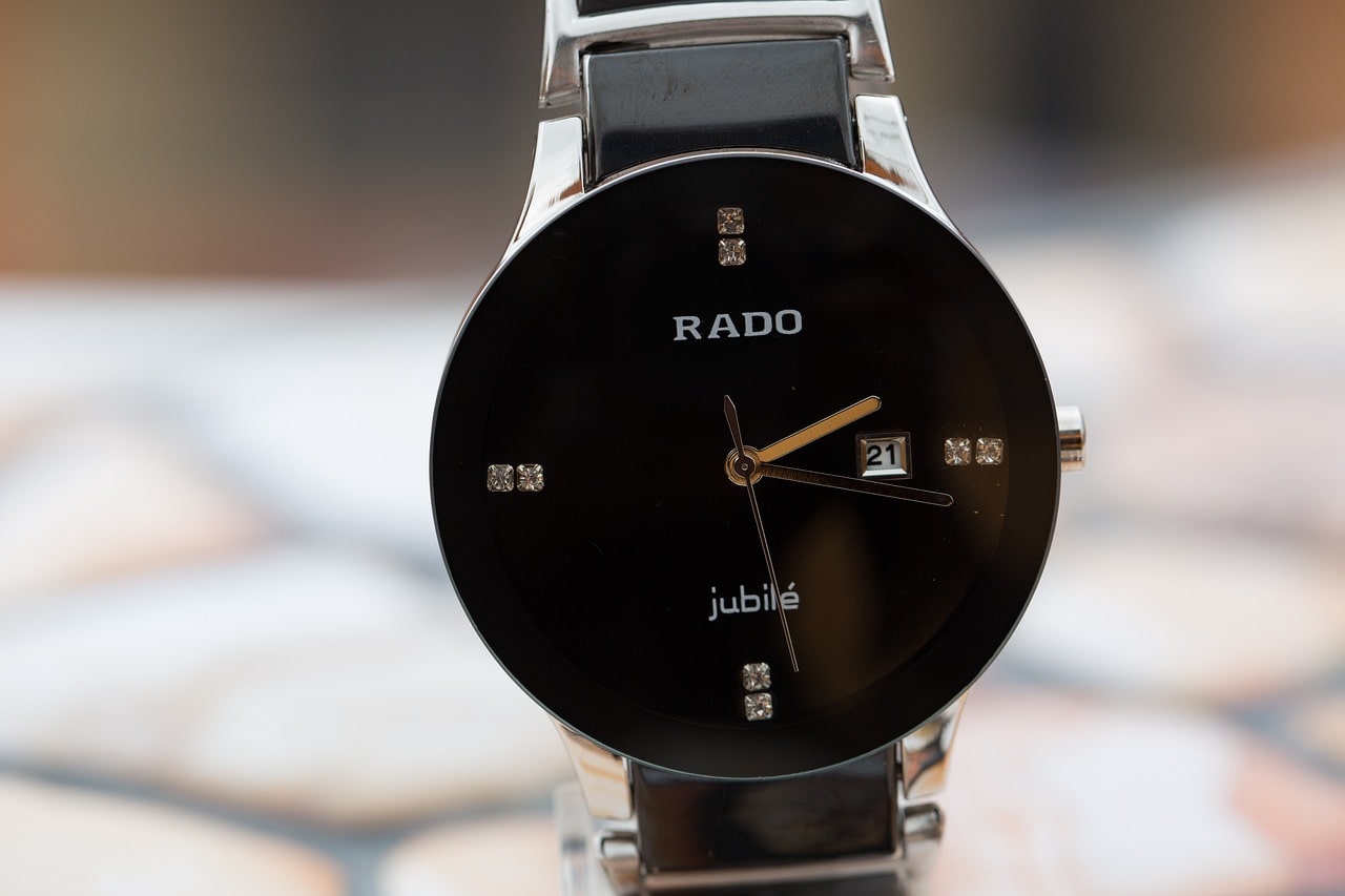 A closeup of a minimalist Rado watch with a black dial.
