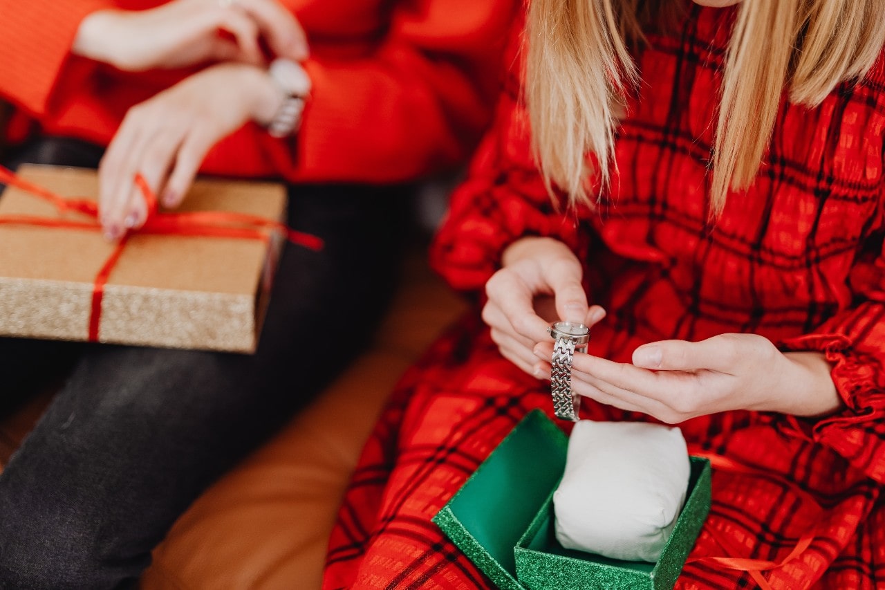 A family sits on a couch and open glittery gifts containing watches.