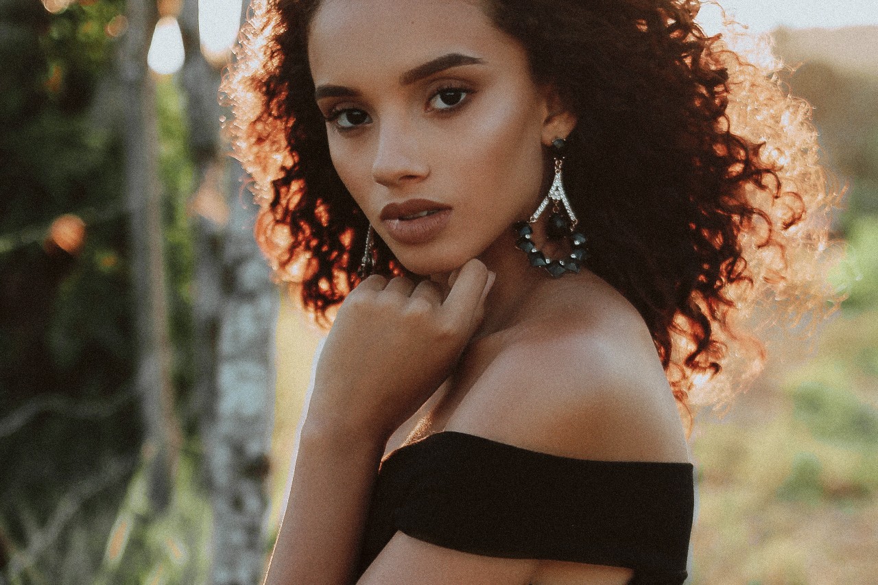 A woman walking in a park wears geometric drop earrings. A woman walking in a park wears geometric drop earrings.