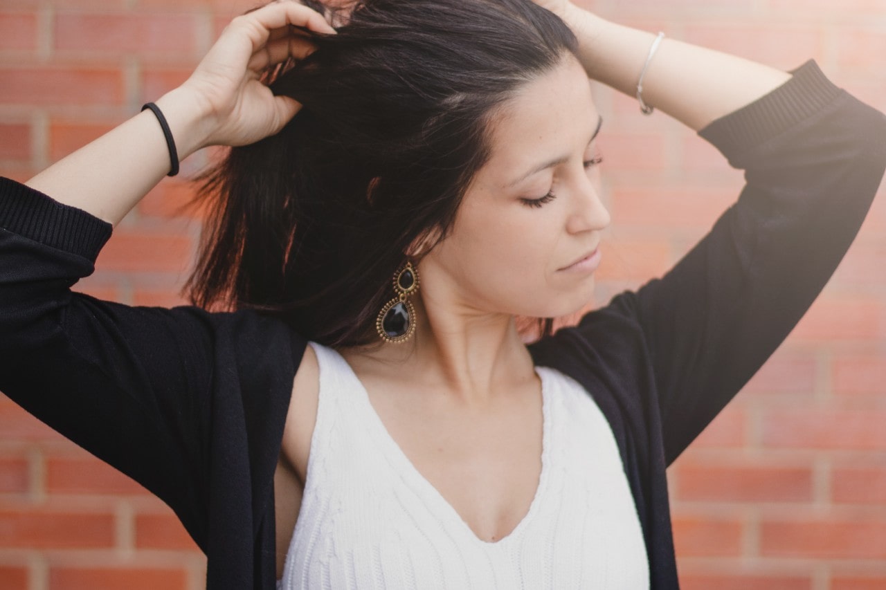 A woman wearing onyx drop earrings runs her fingers through her hair. A woman wearing onyx drop earrings runs her fingers through her hair.