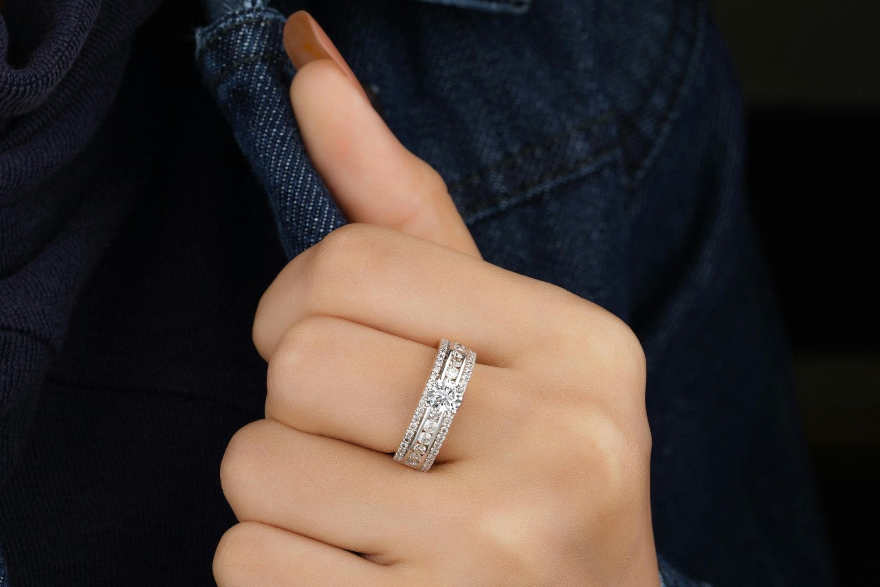 A close-up of a hand wearing an elegant diamond-studded ring, set against a dark denim jacket. A close-up of a hand wearing an elegant diamond-studded ring, set against a dark denim jacket.