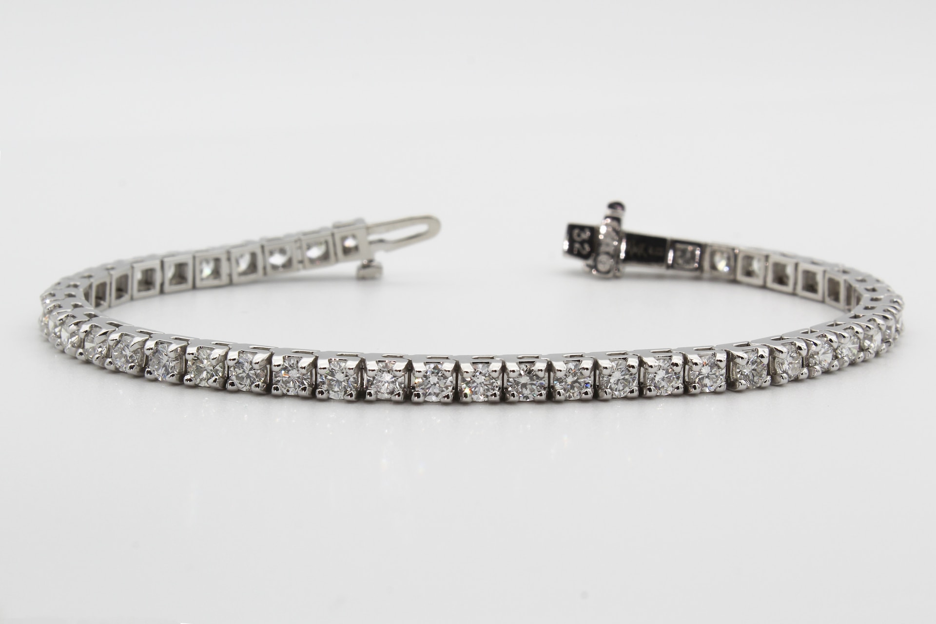 a white gold tennis bracelet featuring a line of round cut diamonds