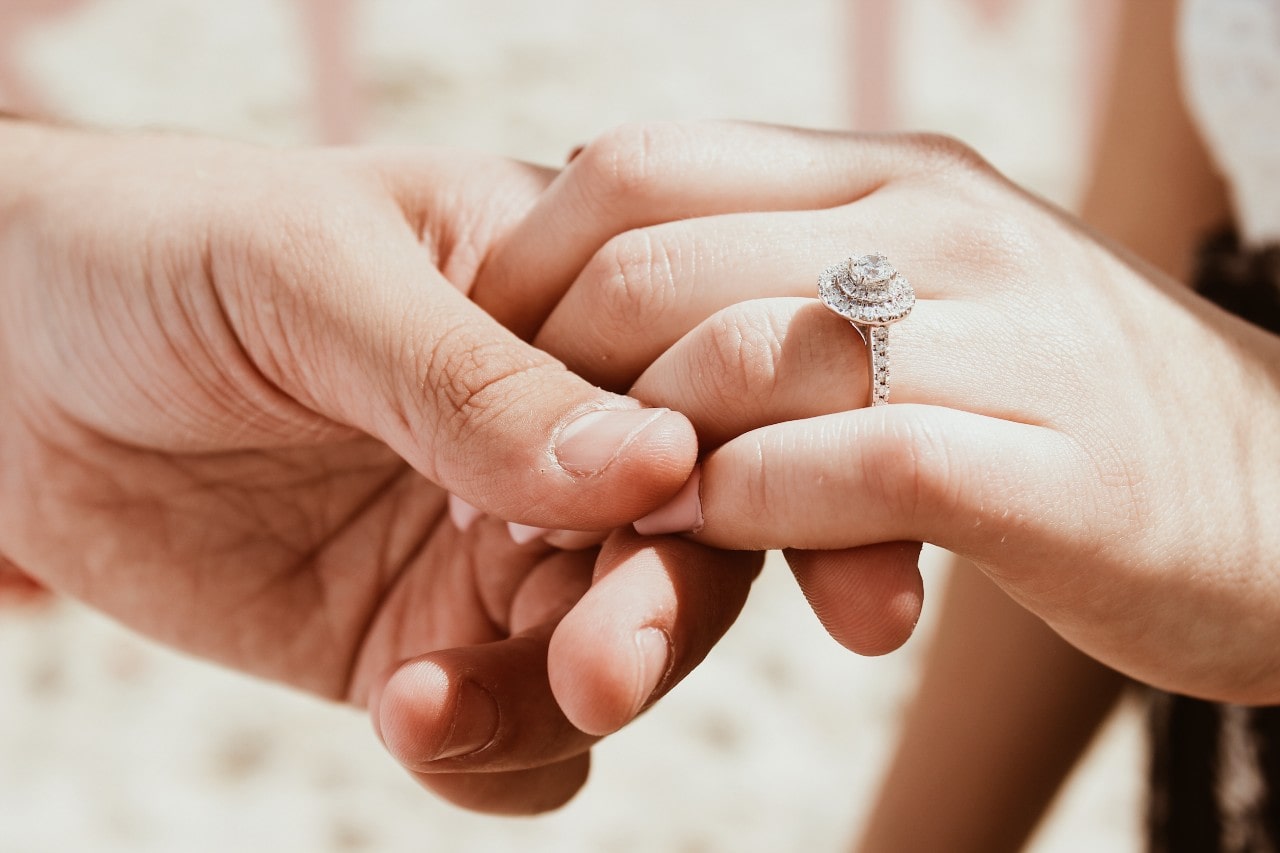 A man is holding a woman’s hand adorned with a sparkling engagement ring, conveying love and commitment. Warm, intimate tones create a romantic atmosphere. A man is holding a woman’s hand adorned with a sparkling engagement ring, conveying love and commitment. Warm, intimate tones create a romantic atmosphere.