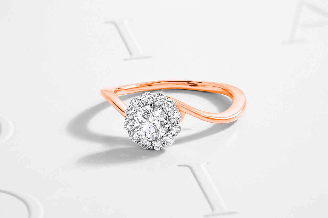 Rose gold ring with a round diamond halo setting on a white background. The elegant curves and shimmering stones evoke a sense of luxury and romance. Rose gold ring with a round diamond halo setting on a white background. The elegant curves and shimmering stones evoke a sense of luxury and romance.