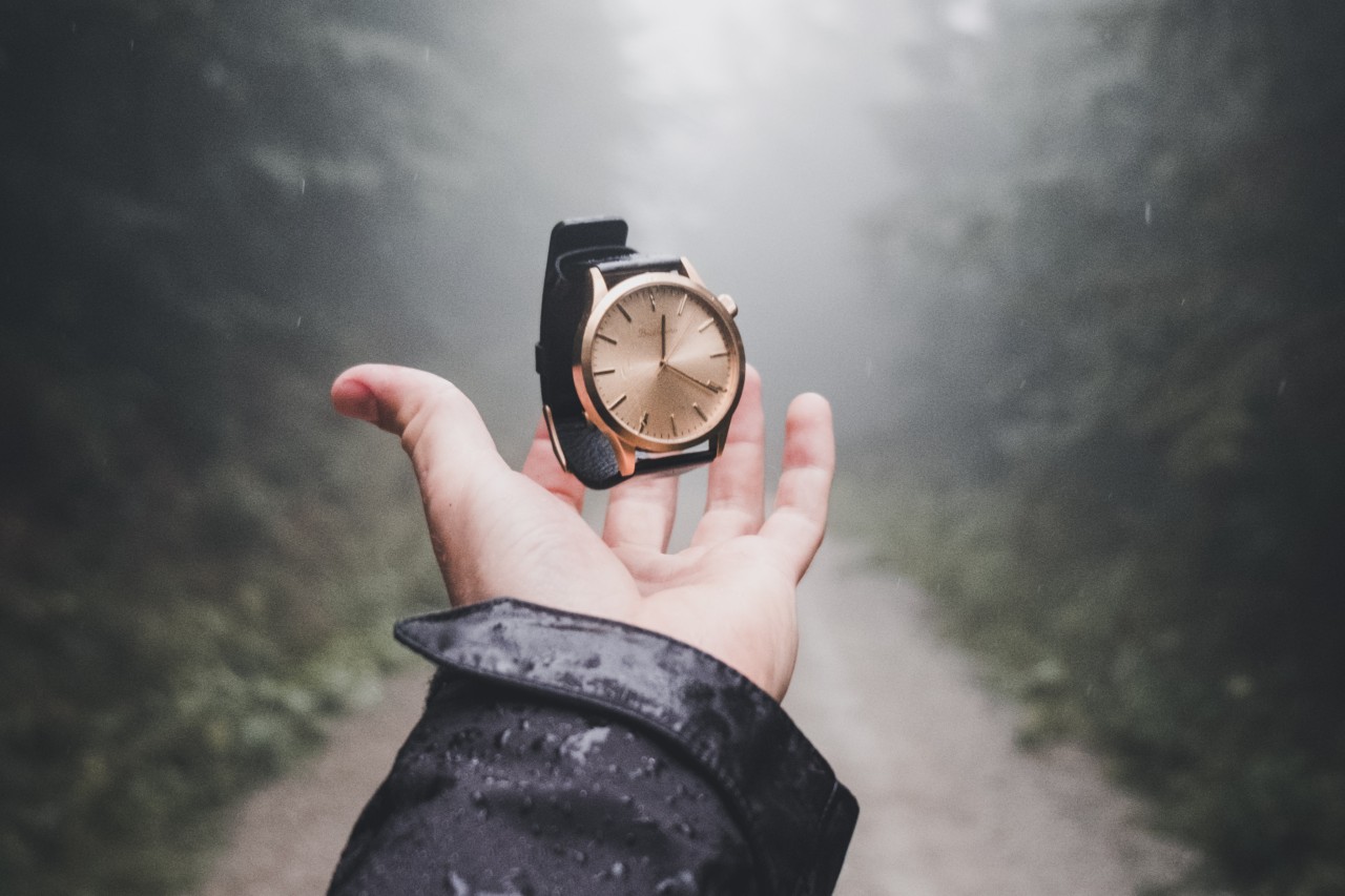 An outstretched hand under a watch suspended in the air