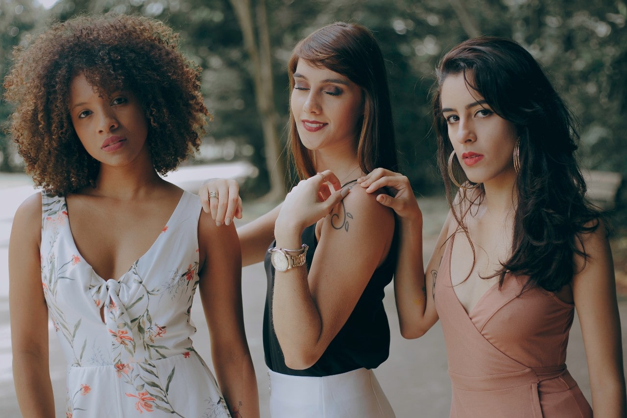 Three women standing together, the woman in the center wearing a mixed metal watch Three women standing together, the woman in the center wearing a mixed metal watch