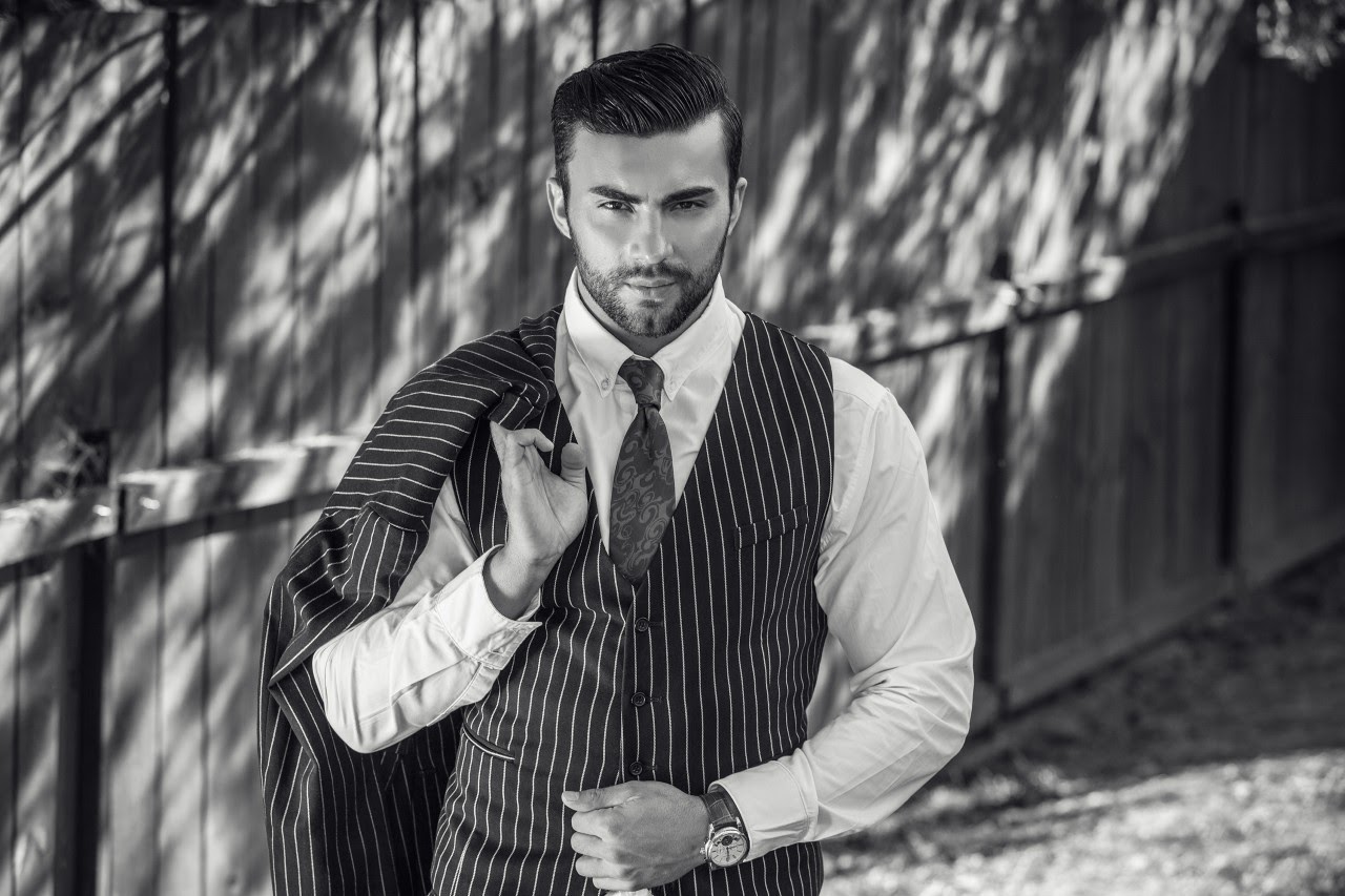 A man in a striped suit set wears a timepiece in his backyard