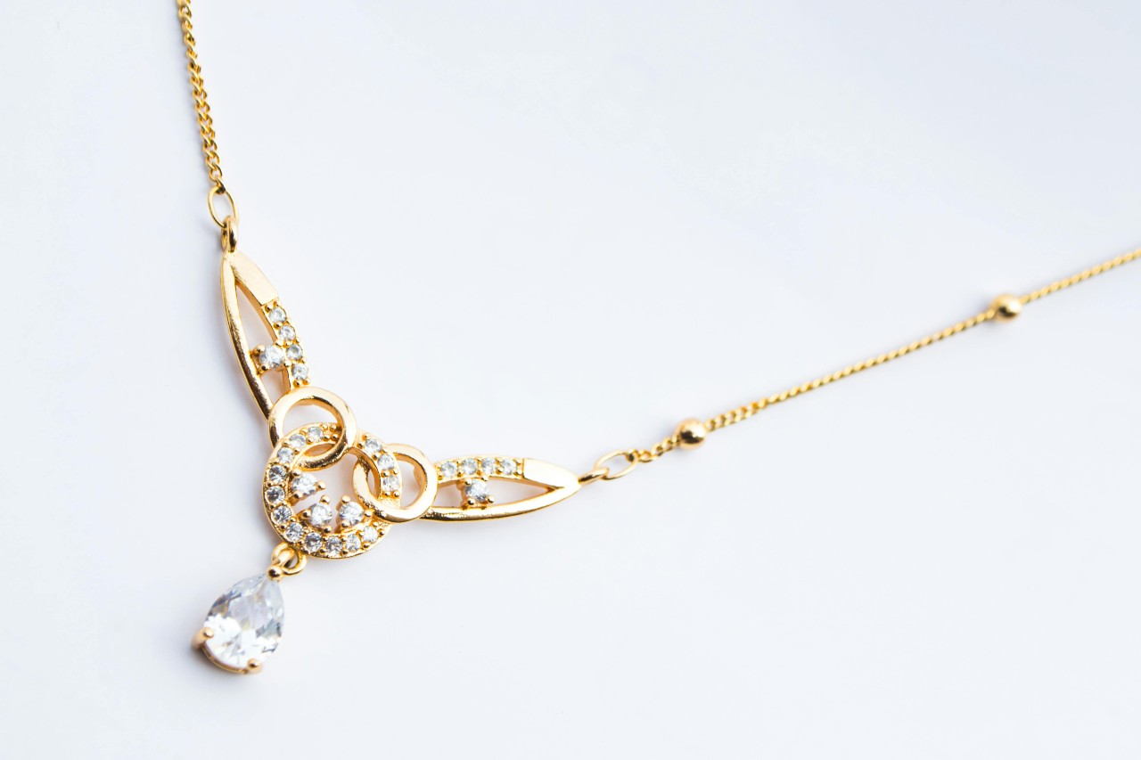 close up image of a yellow gold diamond pendant necklace with an intricate design close up image of a yellow gold diamond pendant necklace with an intricate design