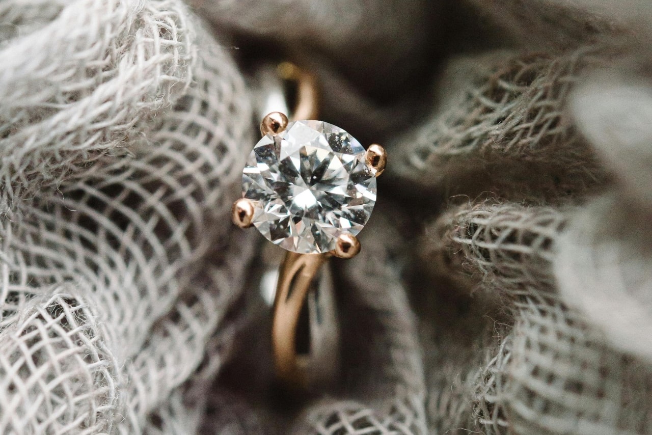 close up image of a mixed metal diamond engagement ring on burlap