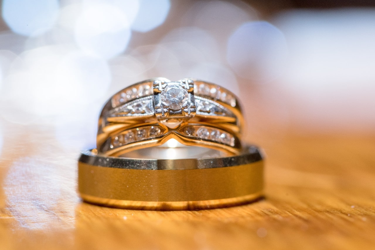 A bridal stack, consisting of a diamond multi-band engagement ring and wedding band with matte polish, on a wooden surface.