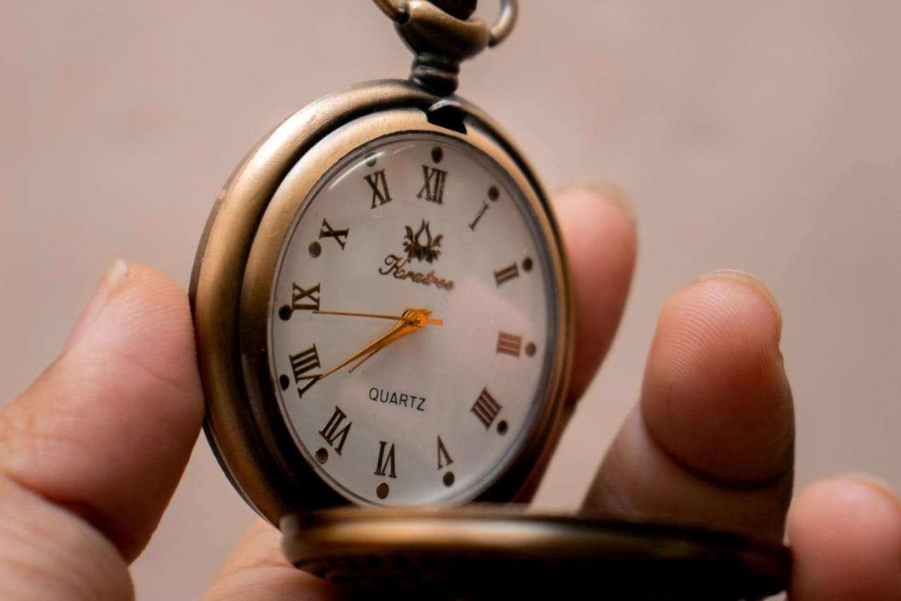 A hand holding a flip watch