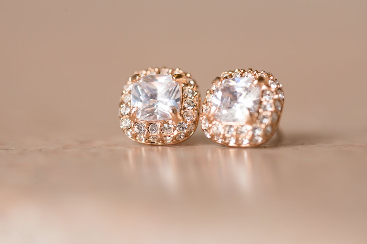 A close-up of beautiful halo stud earrings on a warm backdrop.