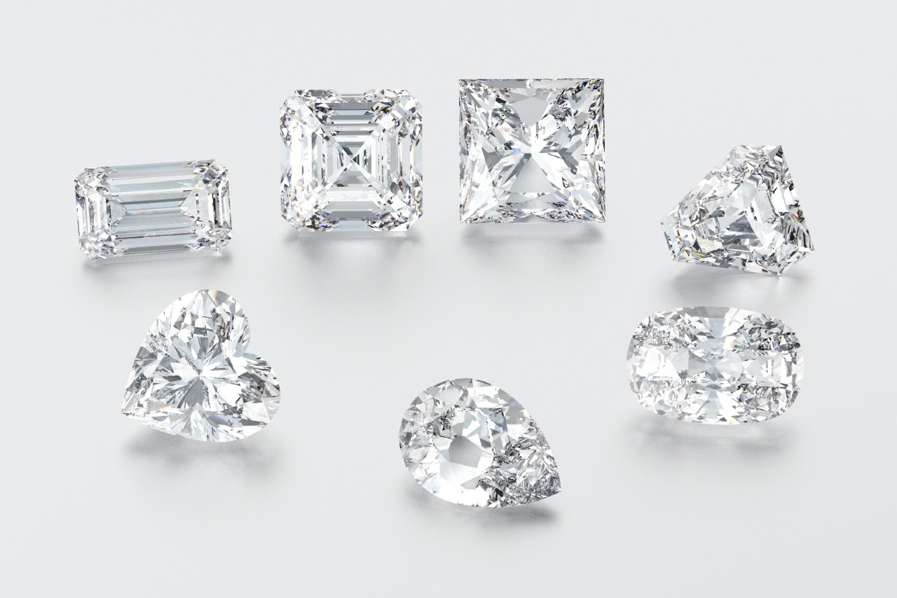 A collection of diamonds in various cuts, including emerald, asscher, princess, trillion, heart, pear, and oval, arranged on a light background.