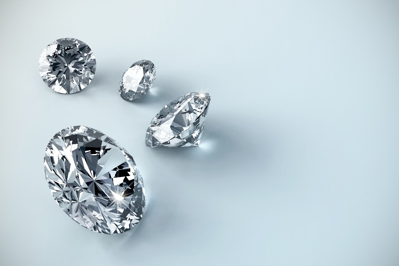 Four round brilliant-cut diamonds rest on a light-blue surface