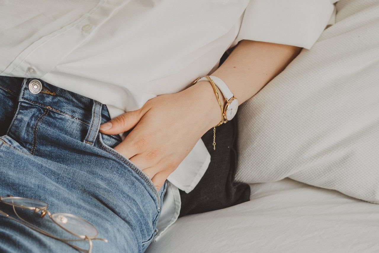 close up image of a woman with her hand in her jean pocket and wearing a white watch