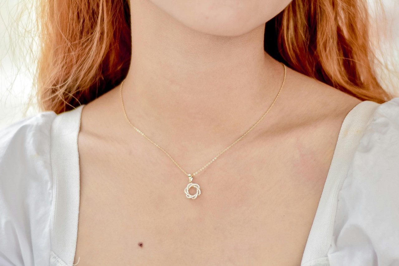 A close-up image of a woman’s neckline adorned with a fine chain pendant necklace.