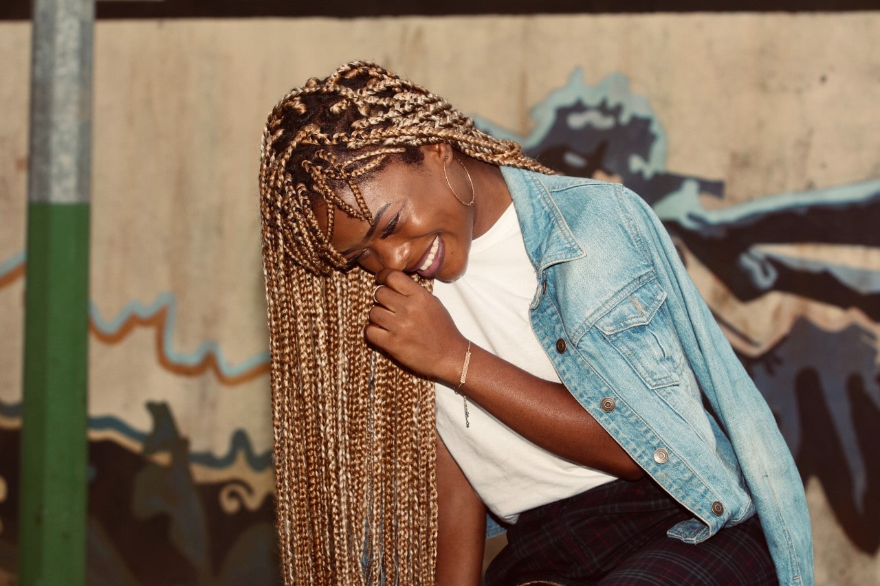 a woman doubled over laughing and wearing a gold bracelet, ring and hoop earrings