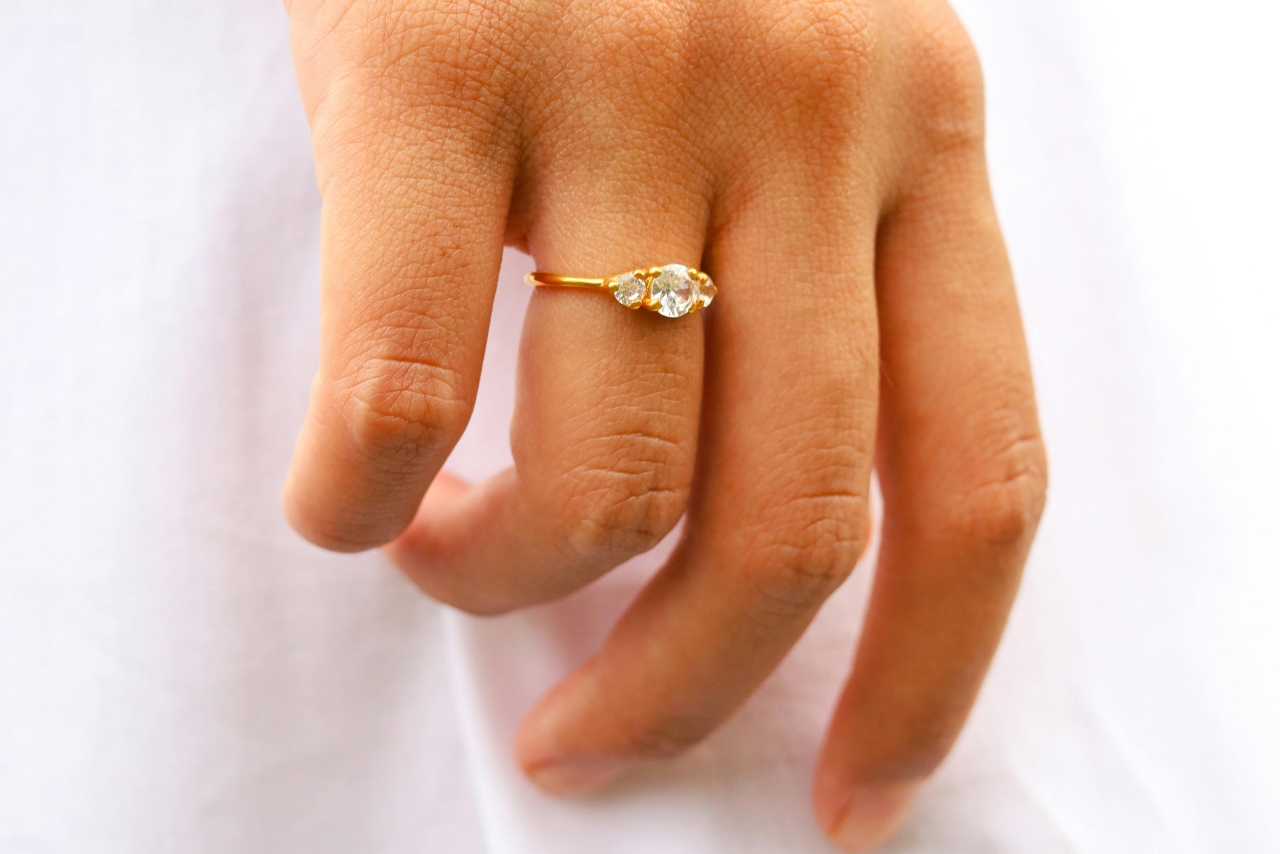 A close-up of a yellow gold three-stone engagement ring.
